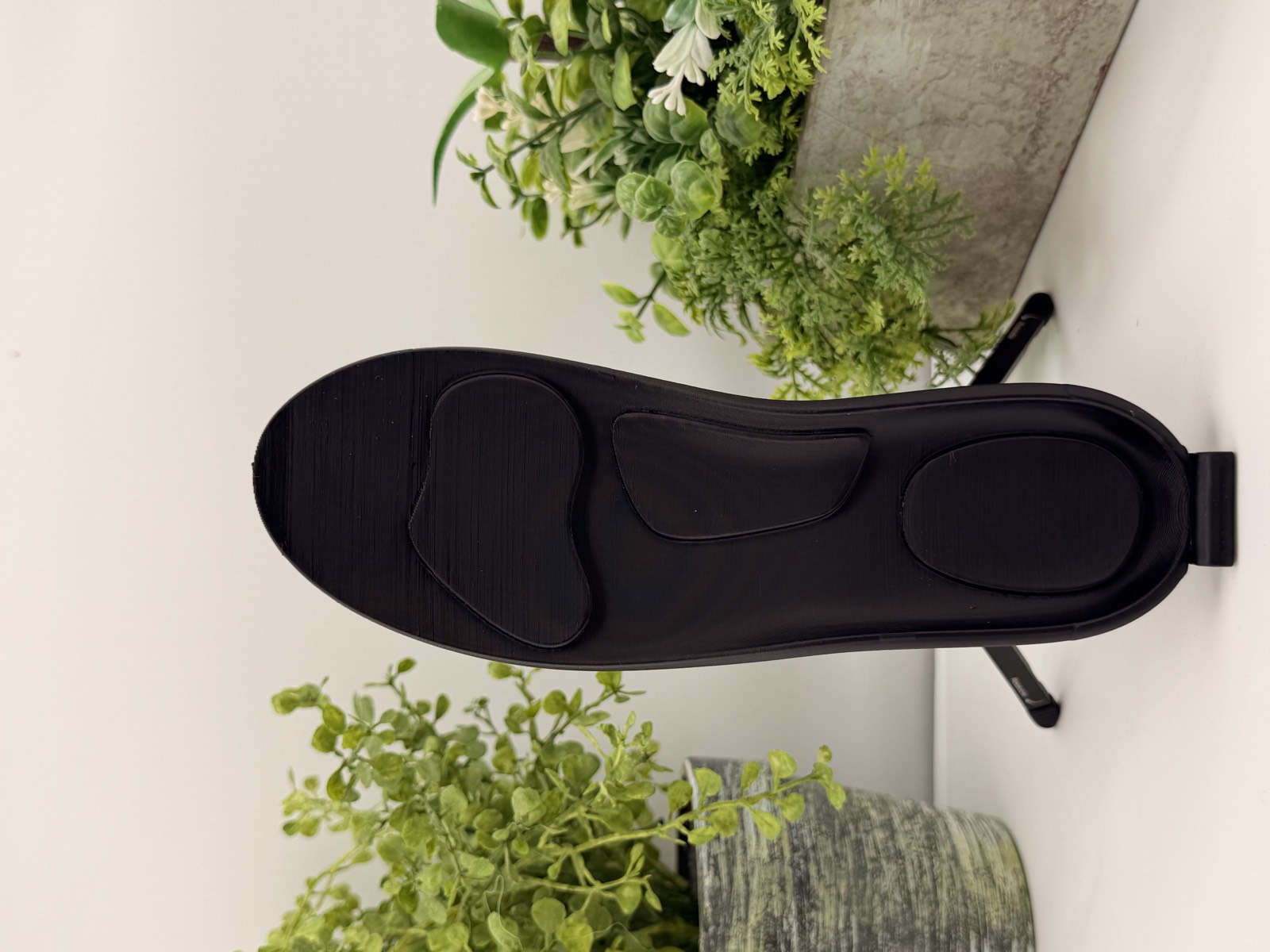 A black NuSoulz insole standing upright, showing its contoured support zones
